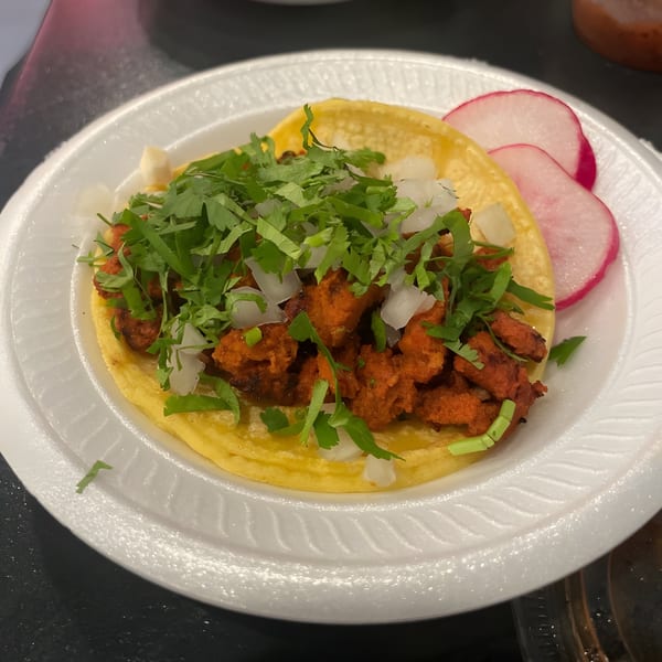 A LA Tacos & Kabobs al pastor taco with cilantro, onions, and radish slices on a white plate.