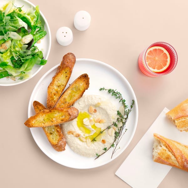 Hummus with toasted bread, a side salad, and a pink drink with a lemon slice.